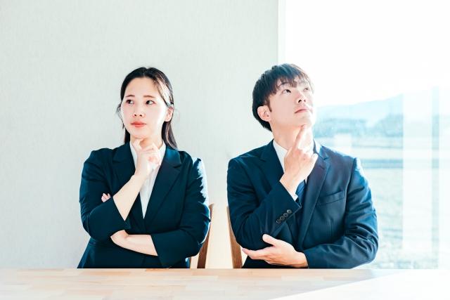 悩んでいる男女の社会人の画像