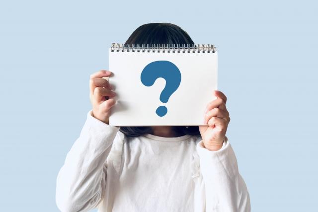 はてなマークが書かれたノートを持つ人